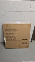 Full view of sealed brown cardboard box containing Safety 1st baby gate.