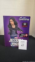 Front views of the Jessica Jones Gallery statue box showing branding and exclusivity to GameStop