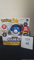 Front view of Pokemon Trainer Guess Johto Edition in box, showing packaging, logo, and toy Pokeball device.