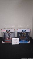 Photo of two boxed Marvel Q Fig figures Deadpool and Venom placed side by side, showing front of packaging and labels.