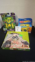 Photo of lot showing sealed Marvel Mechstrike action figure, Hot Wheels toy vehicle box, and Dinosaurs puzzle box.