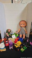 Photo showing the total lot of assorted toys including dolls, plush, figurines, and toy vehicles.