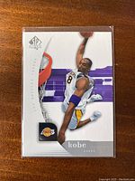Front of the 2005-06 Upper Deck SP Authentic Kobe Bryant card showing the player mid-air dunk in Lakers uniform with SP Authentic and Lakers logo.