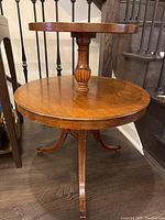 Front view of antique double tier wooden side table showing top and bottom circular tiers and central column support.