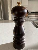 Front view of dark wood Peugeot pepper mill standing on a kitchen counter.