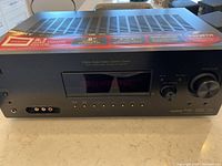 Front view of the Sony HT-DDW990 digital audio/video control center with volume knob, display, and control buttons visible, showing the main unit of the home theatre system.