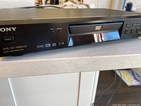 Front view of Sony DVP-NS300 DVD/CD player showing disc tray, control buttons, and logos.