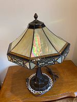 Front view of Tiffany style lamp with detailed opalescent glass shade and metal base on wooden surface.