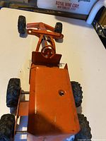 Top angle view of the vintage orange toy tractor showing body and tires