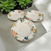 Three Mikasa Country Classics DC014 Fruit Panorama soup bowls with colorful fruit designs arranged on a white surface, showing the top view and the fruit motifs around edges.