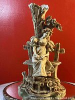 Front view of the Art Nouveau pottery figurine vase showing the seated woman under a tree with vase opening at tree trunk.