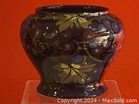 Front and side view showing dark ceramic fruit jar decorated with purple grapes and gold leaves in Jacobean style, bulbous shape with flared base.