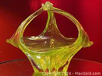 Front angle view of yellow art glass basket vase with arching handle and decorative top knot