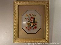 Full view of framed floral artwork showing gold wooden frame and beige mat board.