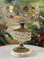Full view of the compote bowl showing crystal bowl, brass stem with hanging prisms, and marble base