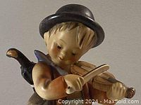 Close-up of front of figurine showing boy playing violin, hat and upper body details.