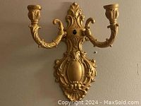Full view of the solid brass candle wall sconce showing two candle holders and decorative backplate.