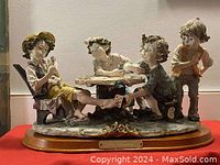 Four children figurine group playing cards, seated around a table, showing detailed facial expressions and hand-painted clothing.