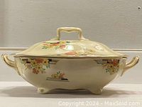 Side view of the antique tureen showing body shape, lid, side handles, and hand painted floral design