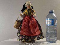 Full view of the vintage French doll next to a water bottle for scale, standing 9.5 inches tall.
