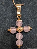 Front view of 10K gold and rose quartz cross-shaped pendant on black background showing the 10K mark on the bail.