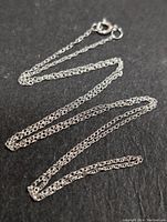 Full view of 16-inch gold chain on black background showing chain lay and clasp.