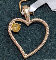 Close-up photo of the gold heart pendant with yellow lab-grown diamond attached to a mounting card.