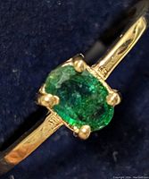 Close-up of oval green emerald set in yellow gold band