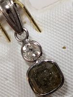 Close-up of the pendant showing white gold mounting with round and square natural diamonds.