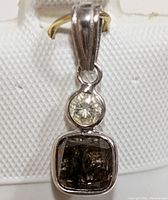 Close-up photo of pendant showing round and cushion cut diamonds and white gold setting.