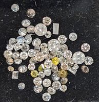 Close-up photo of the loose diamonds displayed on black background showing mixed shapes and colors.