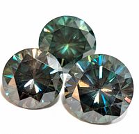 Close-up photo of three round cut moissanite stones with visible facets and light reflections.