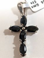 Front view of silver cross pendant featuring five marquise-cut blue sapphire stones prong-set in polished silver with bale for chain attachment.