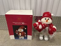 Snowman decoration standing next to original box showing packaging and size (36cm).