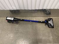 Full side view of Hoover Fusion cordless vacuum laid on floor showing the vacuum stick and handle with detachable handheld unit.