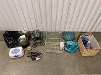 Full lot overview with all items visible: electric lunch box, curling irons, mirror, dish rack, glass bowls, basket with glassware, candles, and black bag.