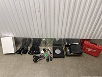 Wide shot of all items in the lot including Sony Discman, cables, chargers, bicycle seat, small electronics, and Milwaukee tool case on metal floor