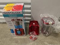 Photo of Nostalgia Retro Slush Drink Maker including main unit, accessories in plastic bags, and original retail box.