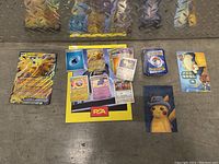 Overview of various Pokemon cards and collectibles laid out on surface including promo cards, deck, and Pikachu items.