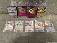 Photo of 10 Surging Sparks Pokémon cards arranged in two rows on a metal diamond plate background. Cards include mostly holographic GX cards and some Trainer and Energy cards.