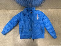 Full front view of blue Kappa Italia puffer jacket laid flat.