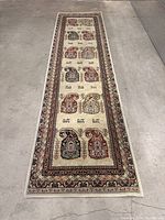 Full-length photo of the vintage Persian runner rug displaying the entire pattern and borders on a concrete floor.