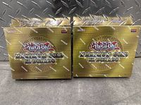 Two sealed boxes of Yu-Gi-Oh Maximum Gold El Dorado trading card booster packs side by side on a metal surface.