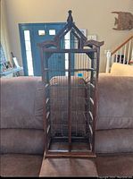 Front view of the wooden bird cage rack showing decorative top, wire mesh sides and multiple doors.