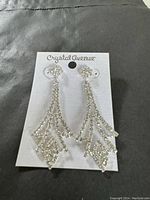 Photo showing Crystal Avenue earrings still attached to original card, silver-tone with clear rhinestones in a geometric drop style.