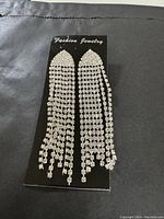 Photo of a pair of long, clear rhinestone fringe earrings on a Fashion Jewelry card.