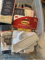 Clear plastic tub containing handmade sewing supplies including a box of satin blanket binding, Wright's single fold bias tape, 3M Command value pack utility hooks, and other fabric items.