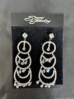 Photo showing a pair of Sassy South dressy formal earrings on black display card with multi-tiered circular rhinestone design and iridescent bead dangles.