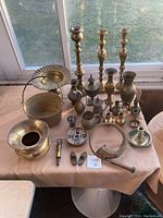 Photo of 25 pieces of assorted brass items on table including candlesticks, vases, pitchers, bucket, bowl, and small decorative pieces.
