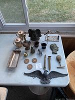Overview of all assorted antique metal items including decorative trays, figurines, candlestick, medallions, and Lincoln's profile relief.